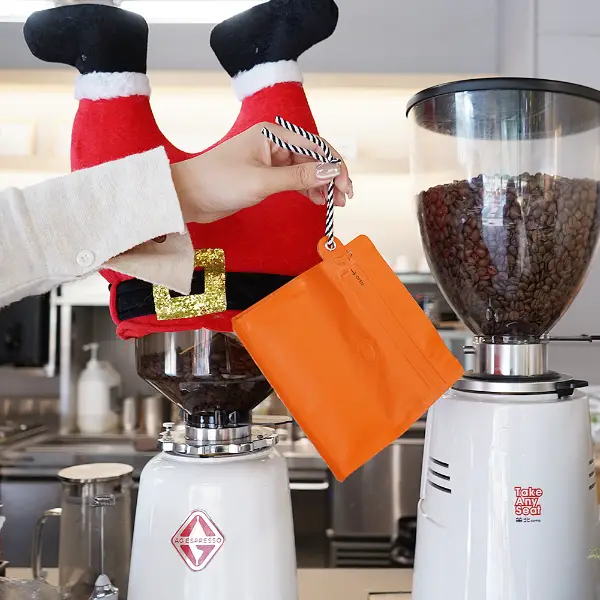 segurando na mão sacos de café de 150g com cordão na cafeteria