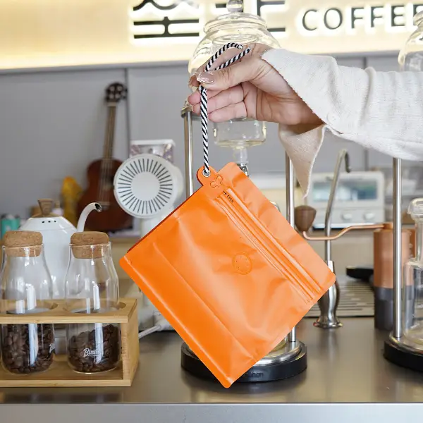 segurando na mão sacos de café de 500g com cordão no espaço de trabalho de café