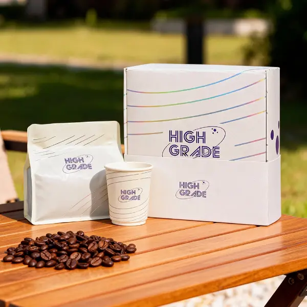 Caixa de café personalizada de marca com saquinho de café e copo de papel combinando, exposta ao ar livre sobre uma mesa de madeira