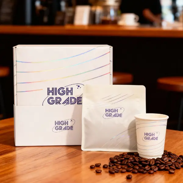 Caixa de café premium personalizada exibida com um saquinho e uma xícara em um ambiente de café