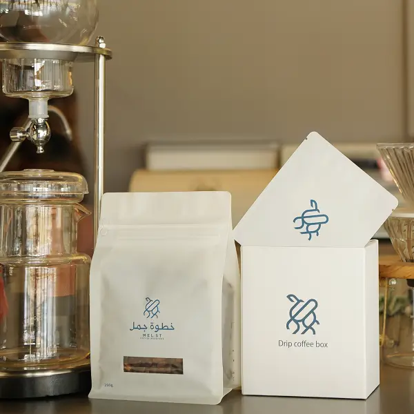 Caixa de papel personalizada premium e sacola de café exibidas em um ambiente de café para exibição de marca