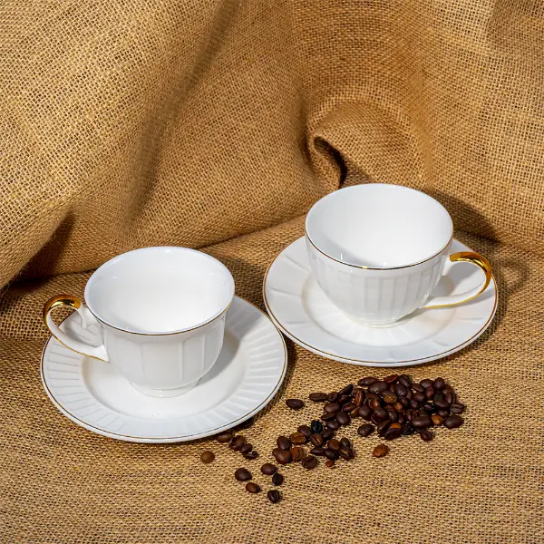Caneca cerâmica em relevo pintada de ouro personalizada com pires exposta com grãos de café