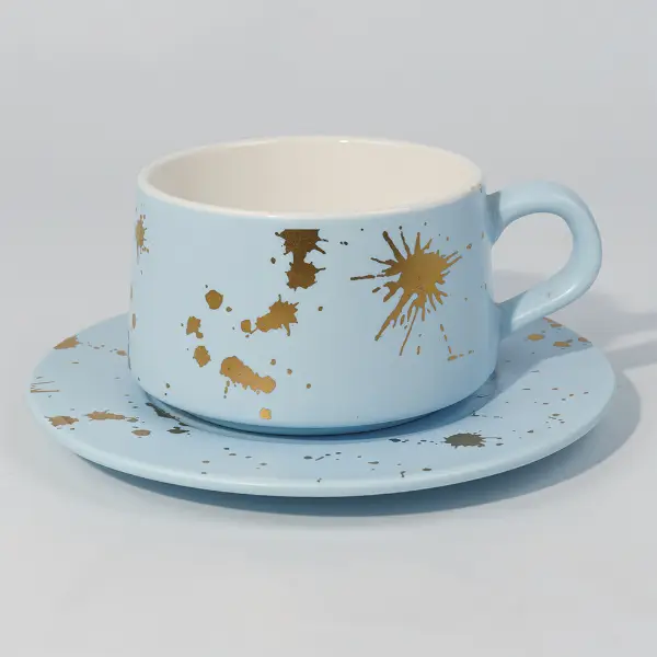 Vista lateral de caneca de café de cerâmica de folha de ouro com desenho de respingos pintado à mão